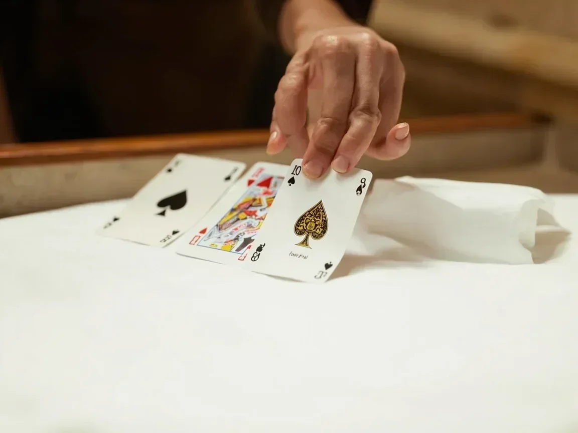 A hand sliding the final card into a same-suit run of four on white linen